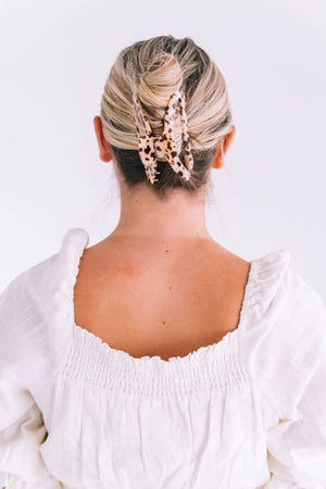 Person with styled hair and a white blouse on a light background
