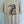 A cream-colored short-sleeve t-shirt hanging on a wooden hanger against a light blue paneled wall. The back of the shirt features a dark brown graphic of a mermaid holding a fish, with the text 'MARSH WEAR' printed vertically.