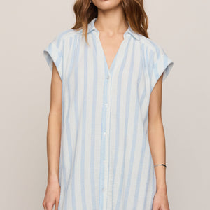 Woman wearing a light blue and white striped dress against a beige background