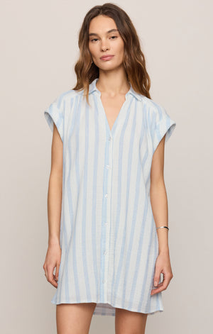 Woman wearing a light blue and white striped dress against a beige background