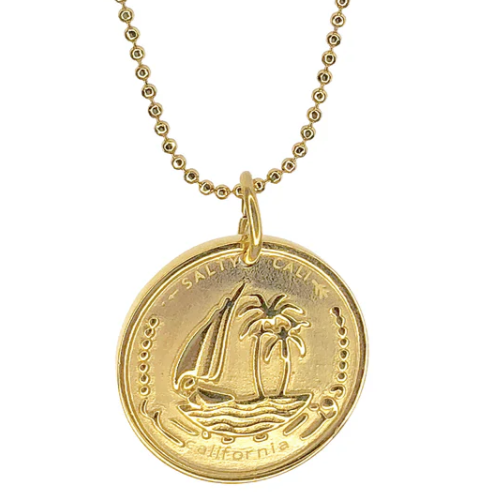 Gold necklace with a coin pendant featuring a sailboat and palm tree design on a white background