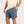Person wearing blue shorts and a beige shirt on a plain background