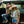 Woman helping a child put on a hat in the back of a black truck with a natural outdoor setting.